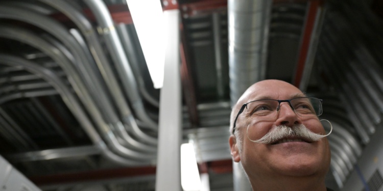 A man in a data center with a large moustache.