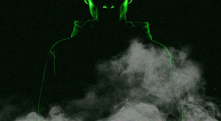 man in darkness wearing a hoodie, lit green