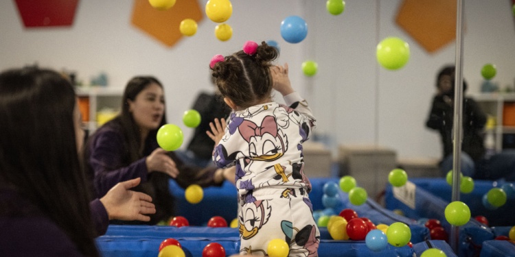 A girl playing with  balls at kindergarten.