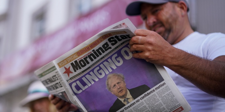A man reading the newspaper with Boris Johnson on the cover.