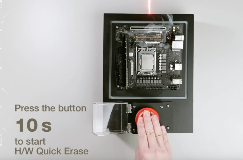 red button, white hand on it,. grey wall, black device with chips