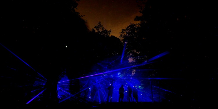 Ravers in blue shining lights in a forest at night.
