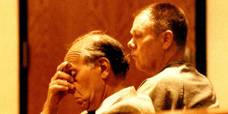 A man holding his head in court.