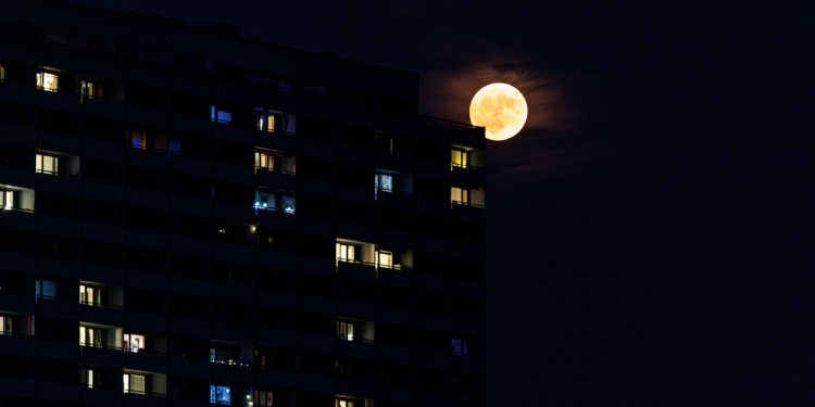 The moon shining on a beautifully lit apartment block.