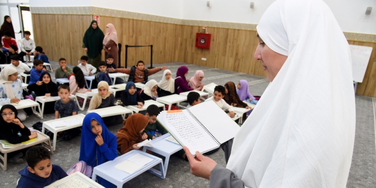 An Arabic teacher reading to her class from a book.
