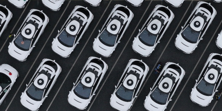 A fleet of Waymo cars in a parking lot.