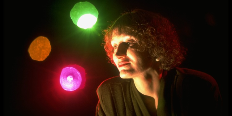 A lady daydreaming with colorful orb lights behind her.