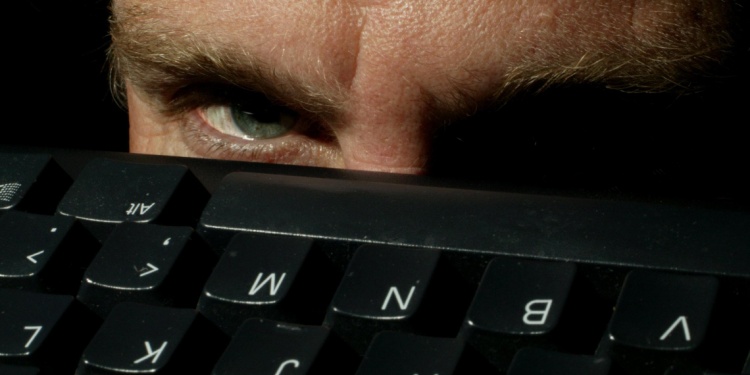A pair of creepy eyes peering over a computer keyboard.