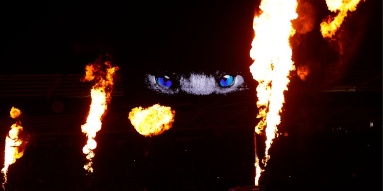 Fire and flares in a dark football stadium.