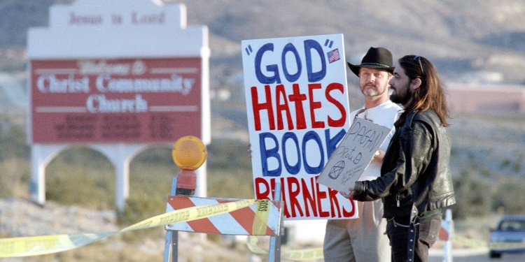 Christian protestors holding a placard saying "God hates book burners"