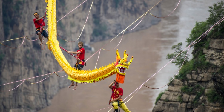 Tightrope walkers doing their job with a Chinese dragon on board.