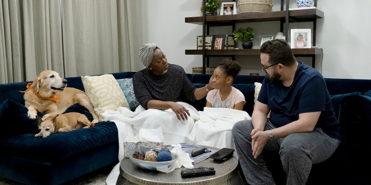 A family having a discussion on the sofa over fomo. Two dogs are on the left.