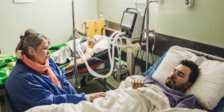A dying patient, in hospital, with a female visitor, potentially his wife.