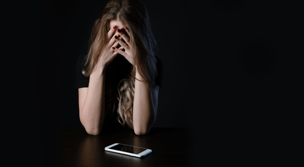 Woman holding head in hands with cellphone