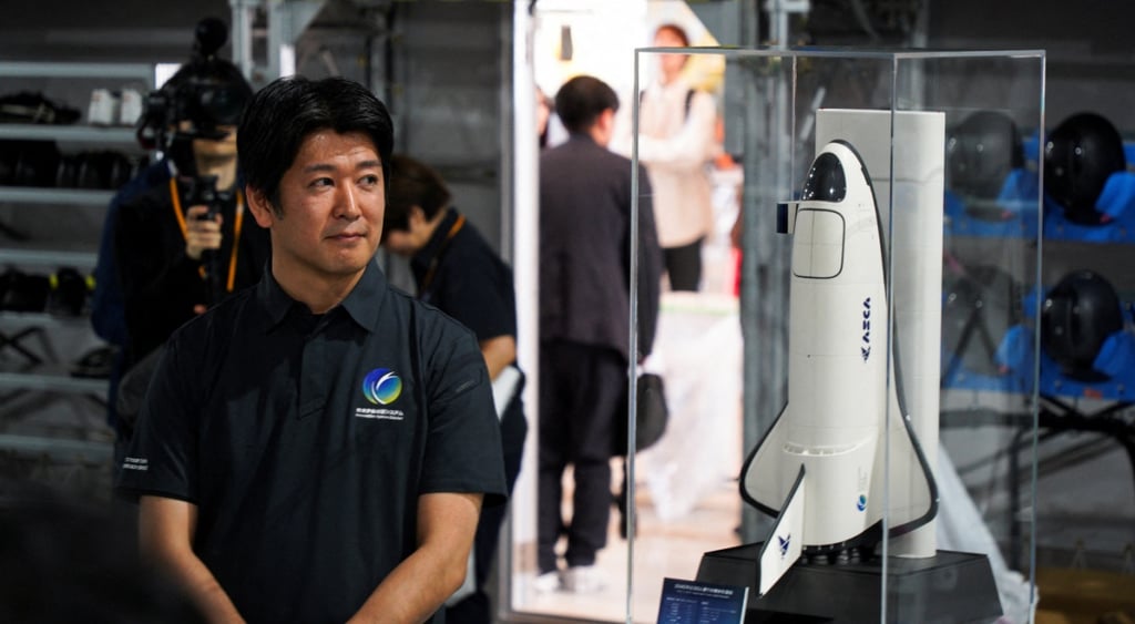 Space Carrier CEO Kojiro Hatada poses with the model of the planned spaceplane ASCA