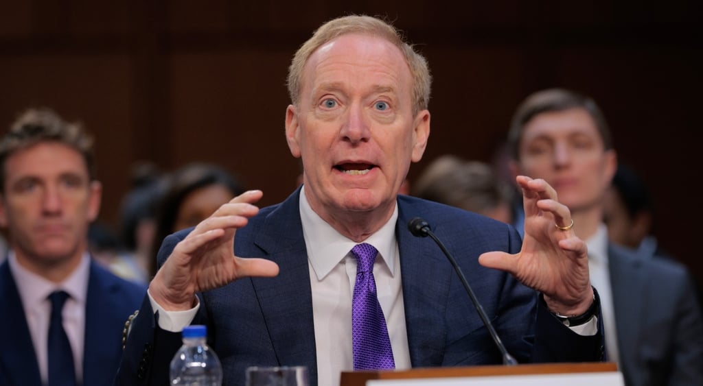 Microsoft Corporation President and Vice Chair Brad Smith with two men in the back