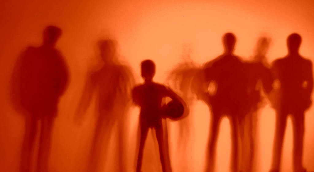 6 brown adult shadows behind an orange filter and one boy shadow with ball