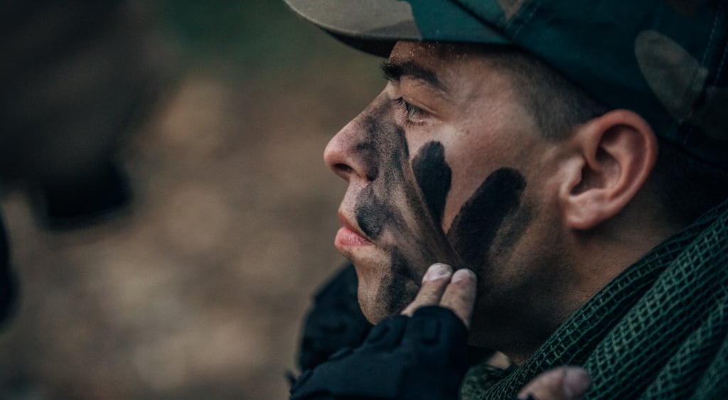 black man, black make up, army had and top, brown and green
