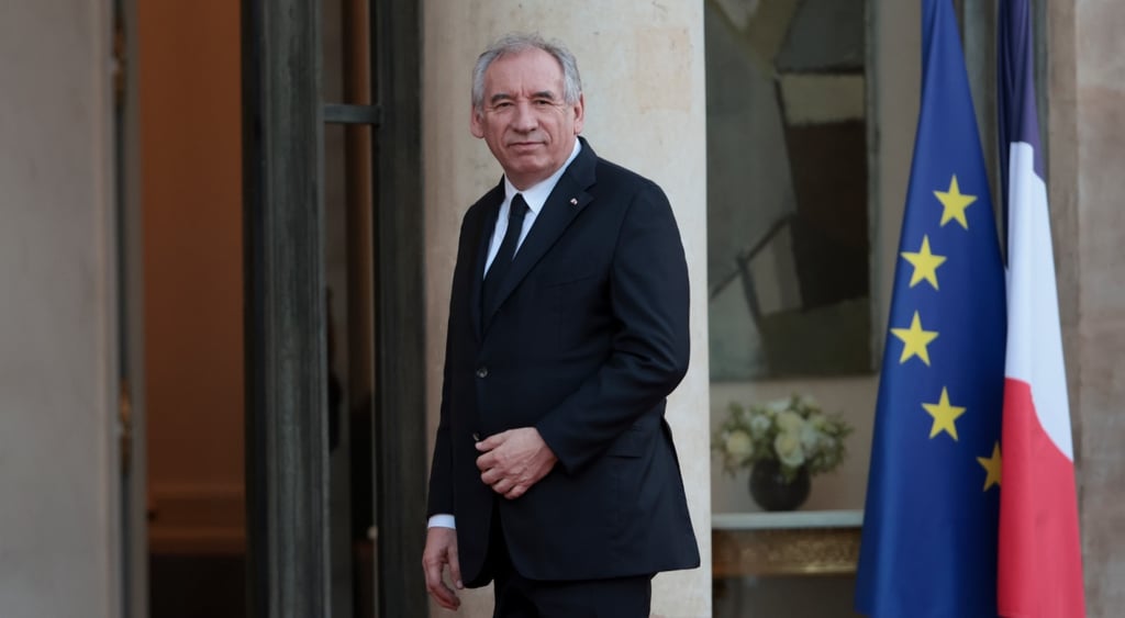 old man in black suit, white shirt, back tie, grey hair, france and EU flag