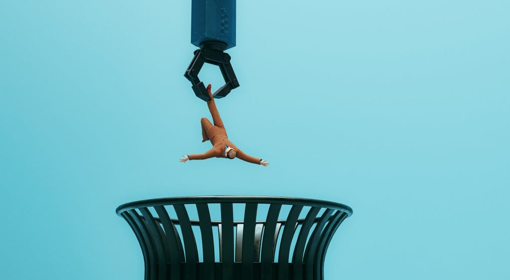 robot hand throws human in brown suit to black trash bin