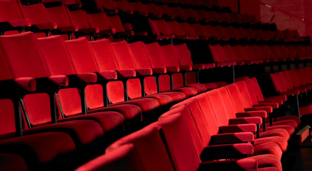 red cinema chairs with arm rests in four line at dark cinema