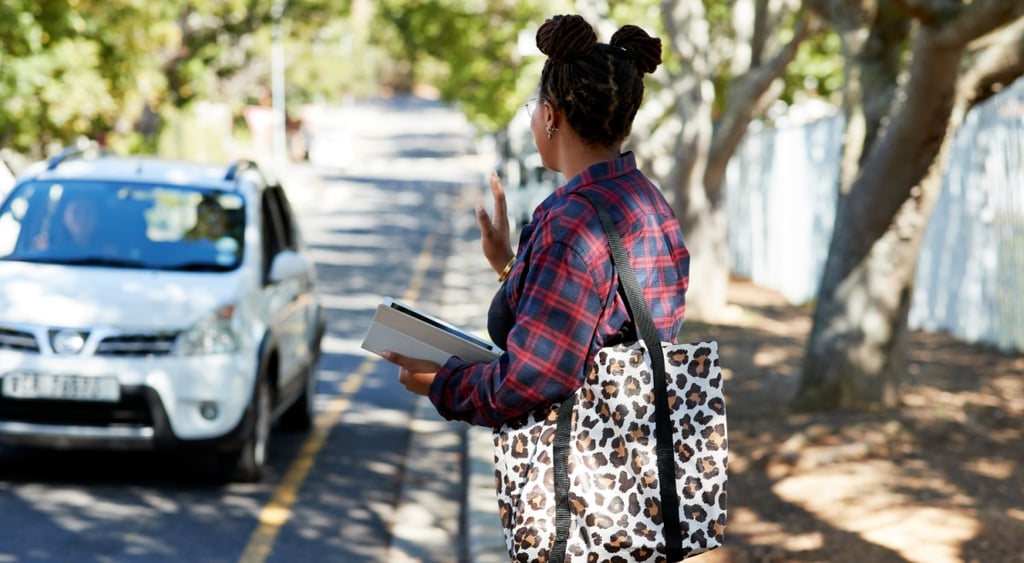 black woman, white car, street, gree leafy trees