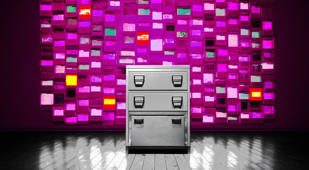 grey file cabinet, pilk, green ad red notes on wall behind, grey wood floor