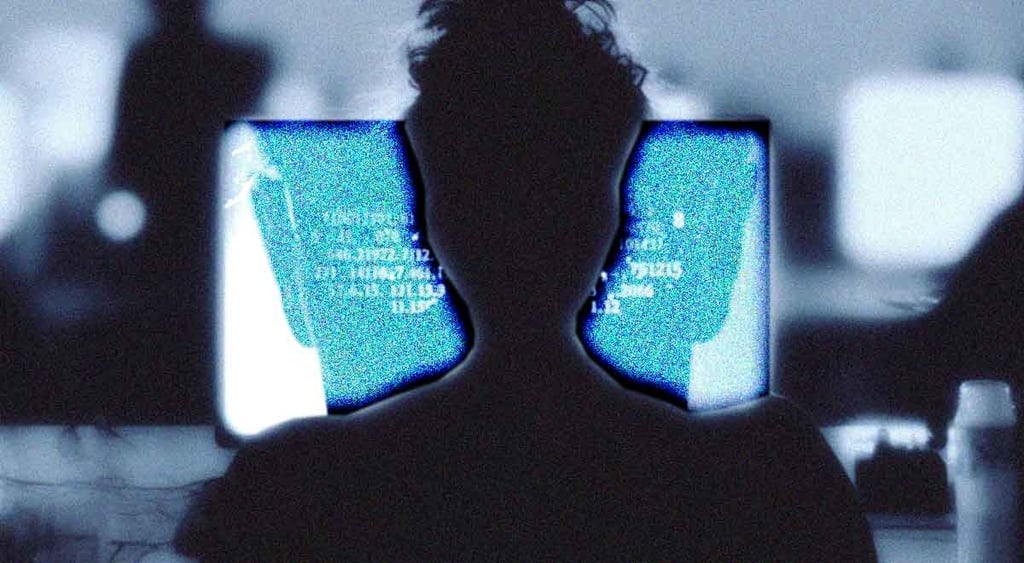 A silhouette of a human writing at a computer terminal.