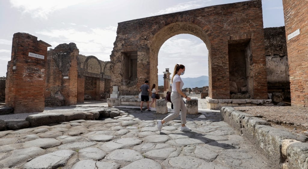 suny day in Italy, female tourist in chaki shorts an white t-shirt walks in ruins