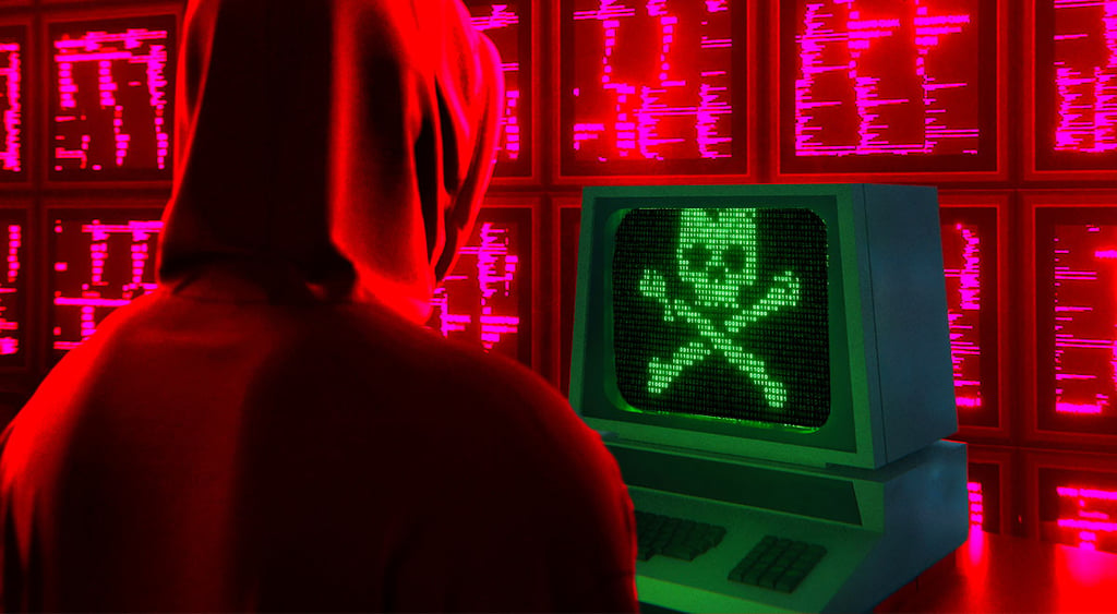 Hacker facing screen with scull; cyber threat