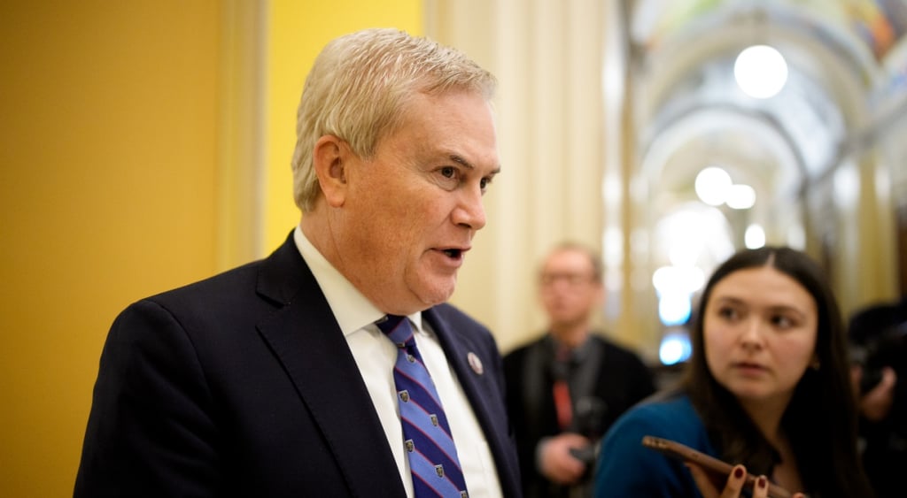 Chairman Rep. James Comer, blonde middle aged man in black suit, white shirt, yellow wall