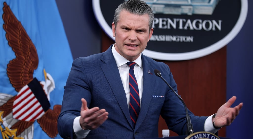 US Secretary of War Pete Hegseth, dark blue suit, white collar shirt, dark red tie, pentagon
