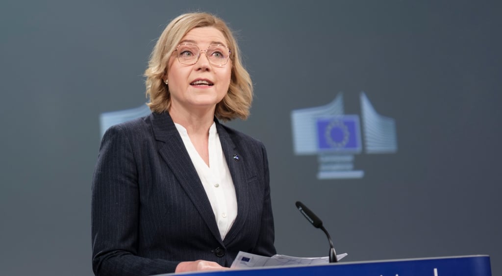 blonde woman, hair to shoulders, black jacket, white shirt, EU comission photo wall