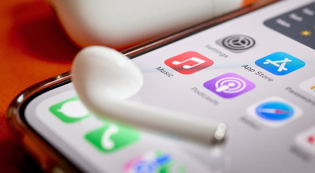 Airpod on top of iPhone screen displaying Apple Music app, Podcasts