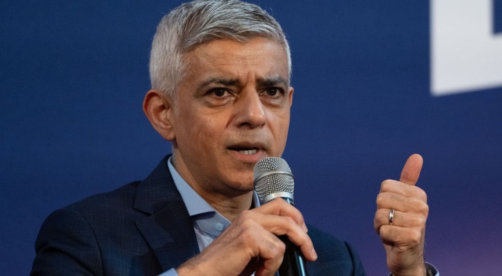 Sadiq Khan, Mayor of London, grey microphone, gold ring, thumb up, grey hair, blue shirt