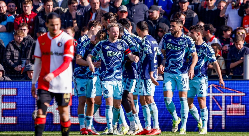 ajax_team_blye shirts, white shorts, football fans in the back