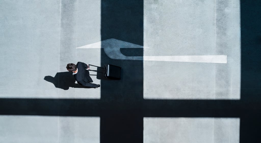 Businessman, black suit, suitcase arrow shadow on grey pavement