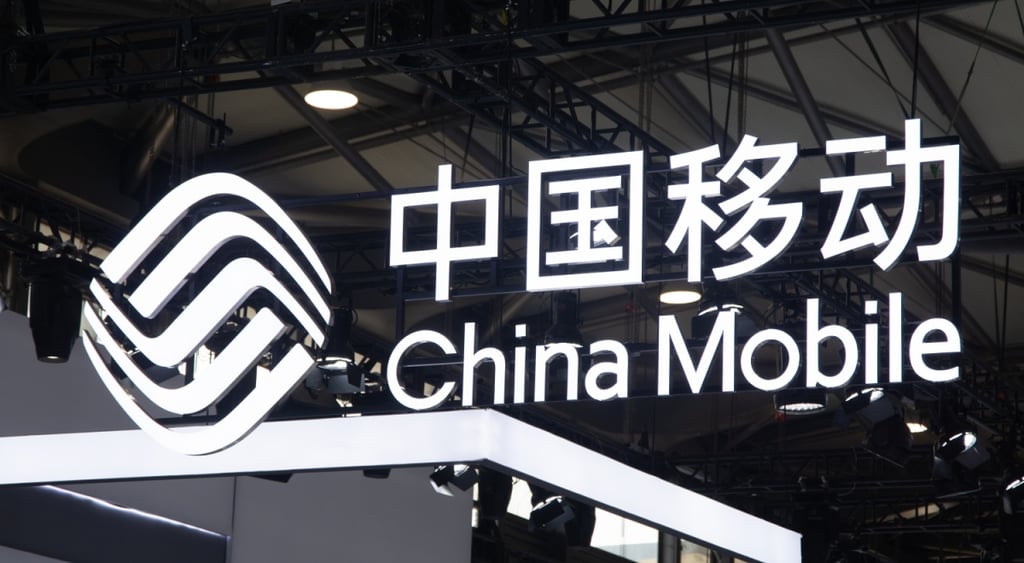 china mobile logo, white latin and chinese letters lit up in black background over a stand
