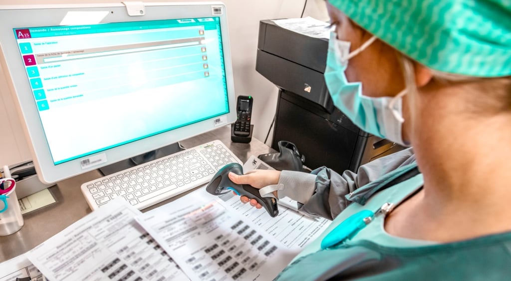 hospital technician scans documents, green scrubs, monitor, medical documents on paper