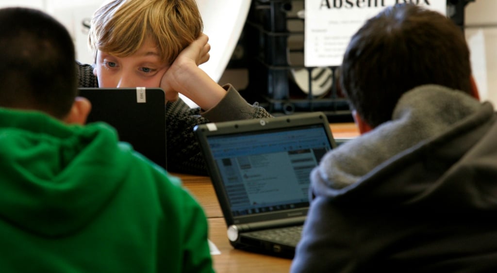 three young teens on black laptops, blonde buy, green jumper, screens,