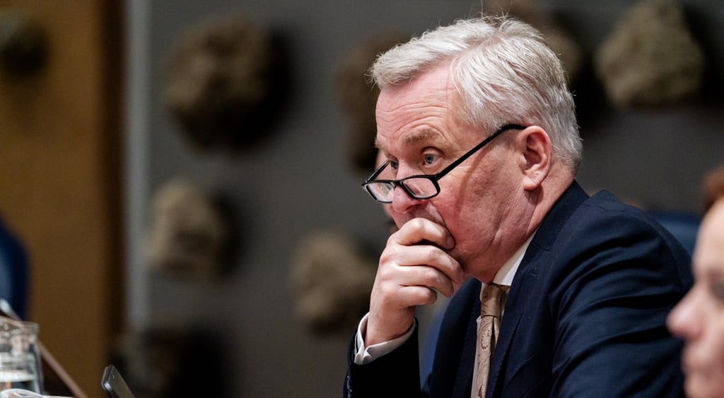 Eric van der Burg, grey hair, right side face profile, right hand on mouth, black glasses frames