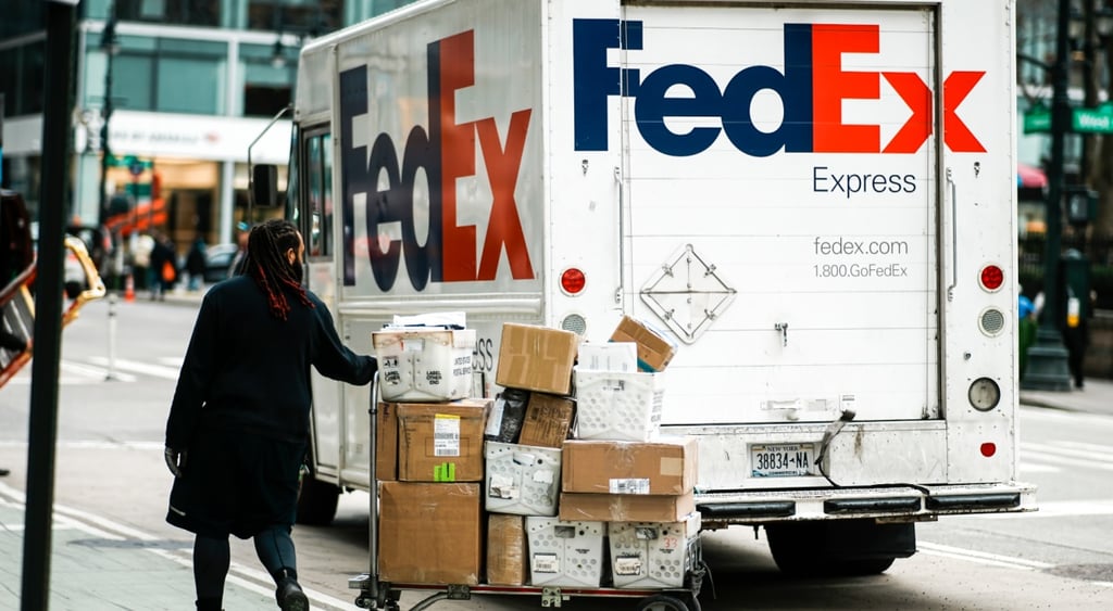 FedEx brown boxes, FedEX logo on white truck, man in black coat, brades, grey street