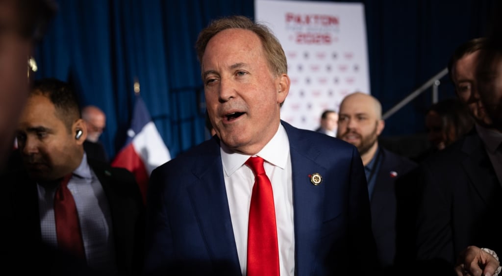 ken praxton, dark blue suit, white shirt, red tie, navy blue curtain in the back, other men in red ties
