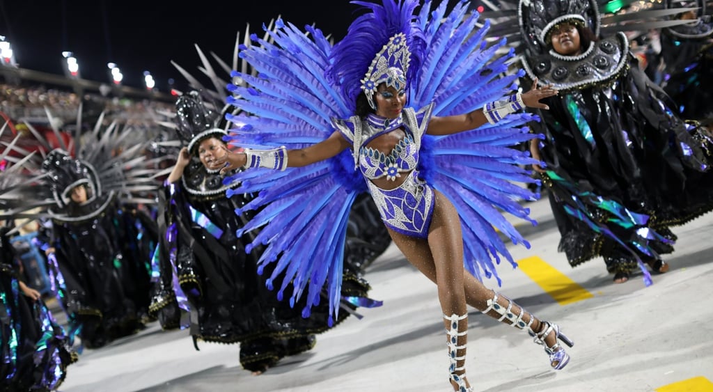 black female samba dancer, rio parade in Brazil, blue feathers, black dancers in black costumes,