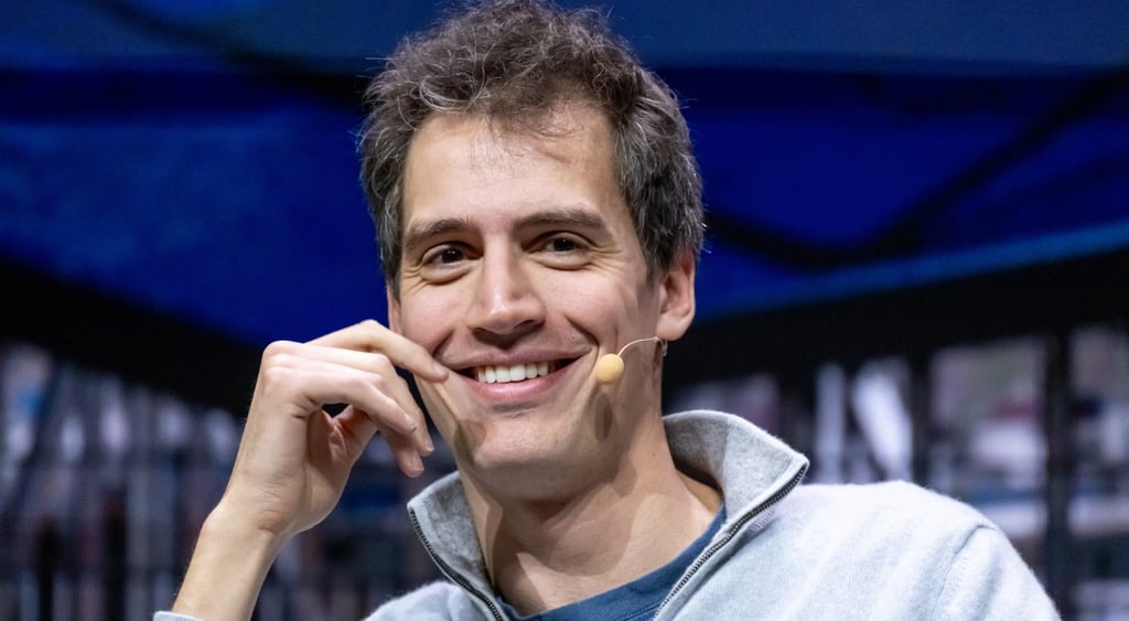 Arthur Mensch, grey jersey, right hand next to face, smiling ,dark hair, white male, white teeth