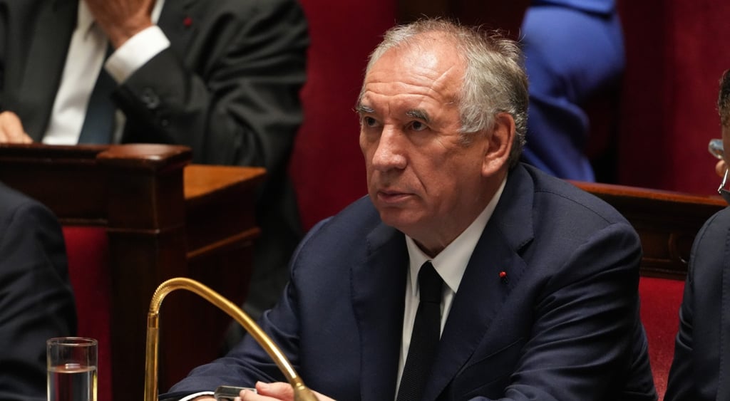 Francois Bayrou, old man, band forehead, grey hair on sides, golden microphone, black suit