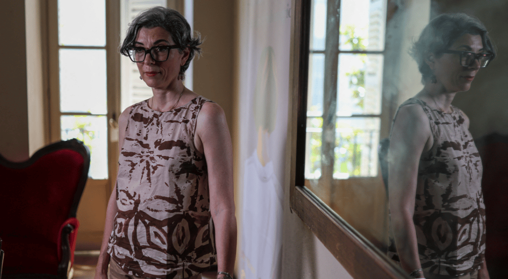 italian white woman, tall windows, grey hair, reflection in mirror, dress, thick black glasses frames