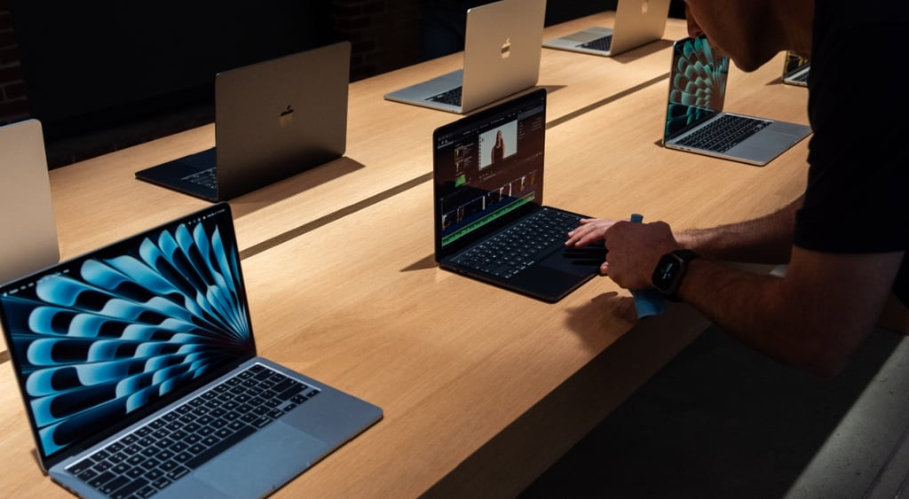 two Apple 13-inch M5 MacBook Air, dark room, white hands