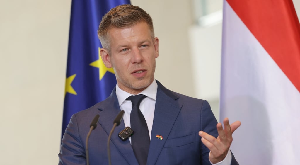 Peter Magyar, dark blue suit, white shirt, dark tie, EU flag, blue with two yellow stars, talking