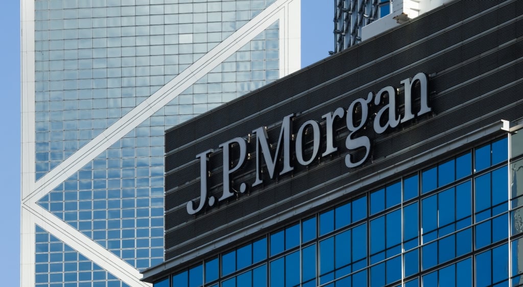 J.P.Morgan sign on black tiles above tall dark blue glass building, light blue sky